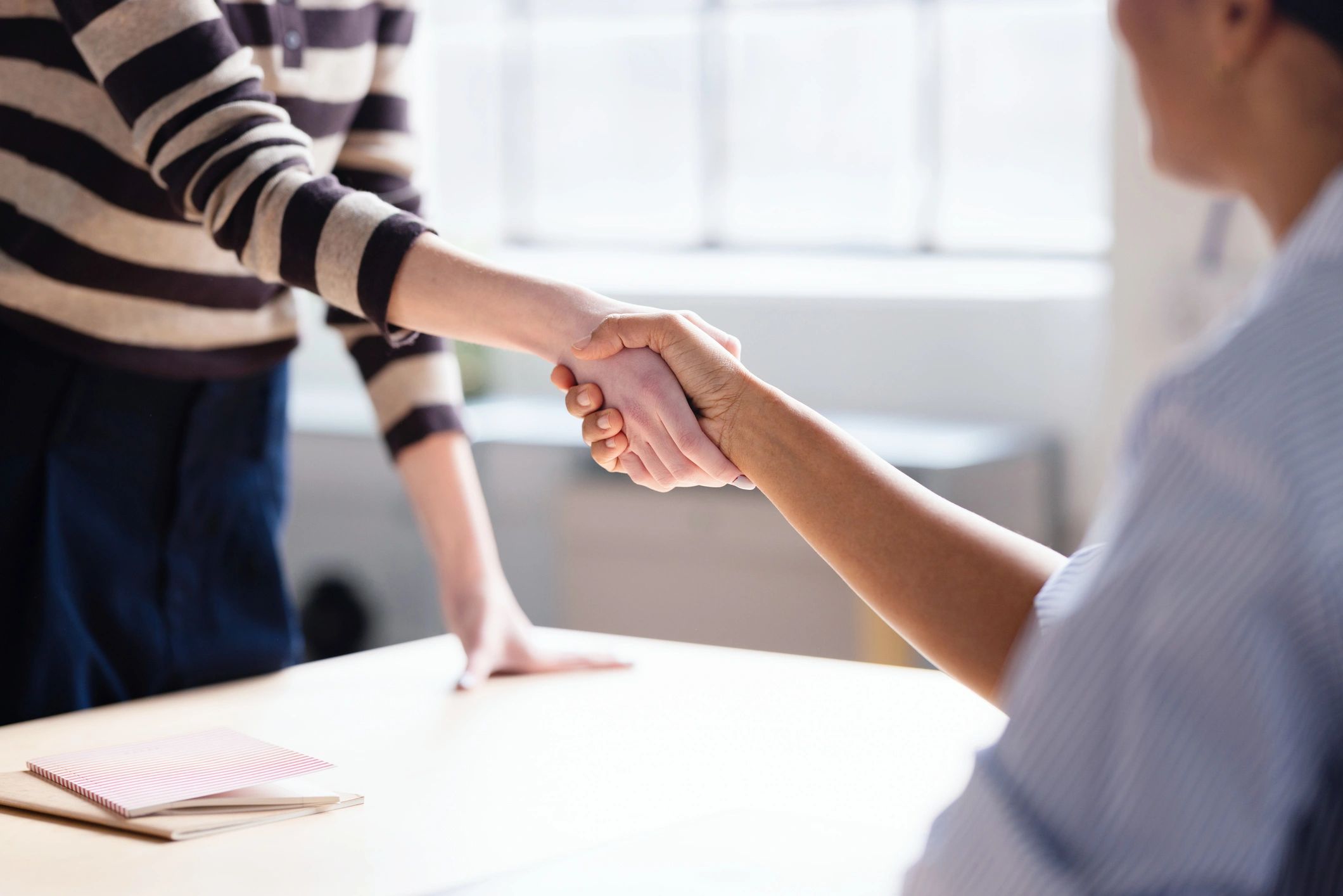 Two professionals shaking hands across a desk