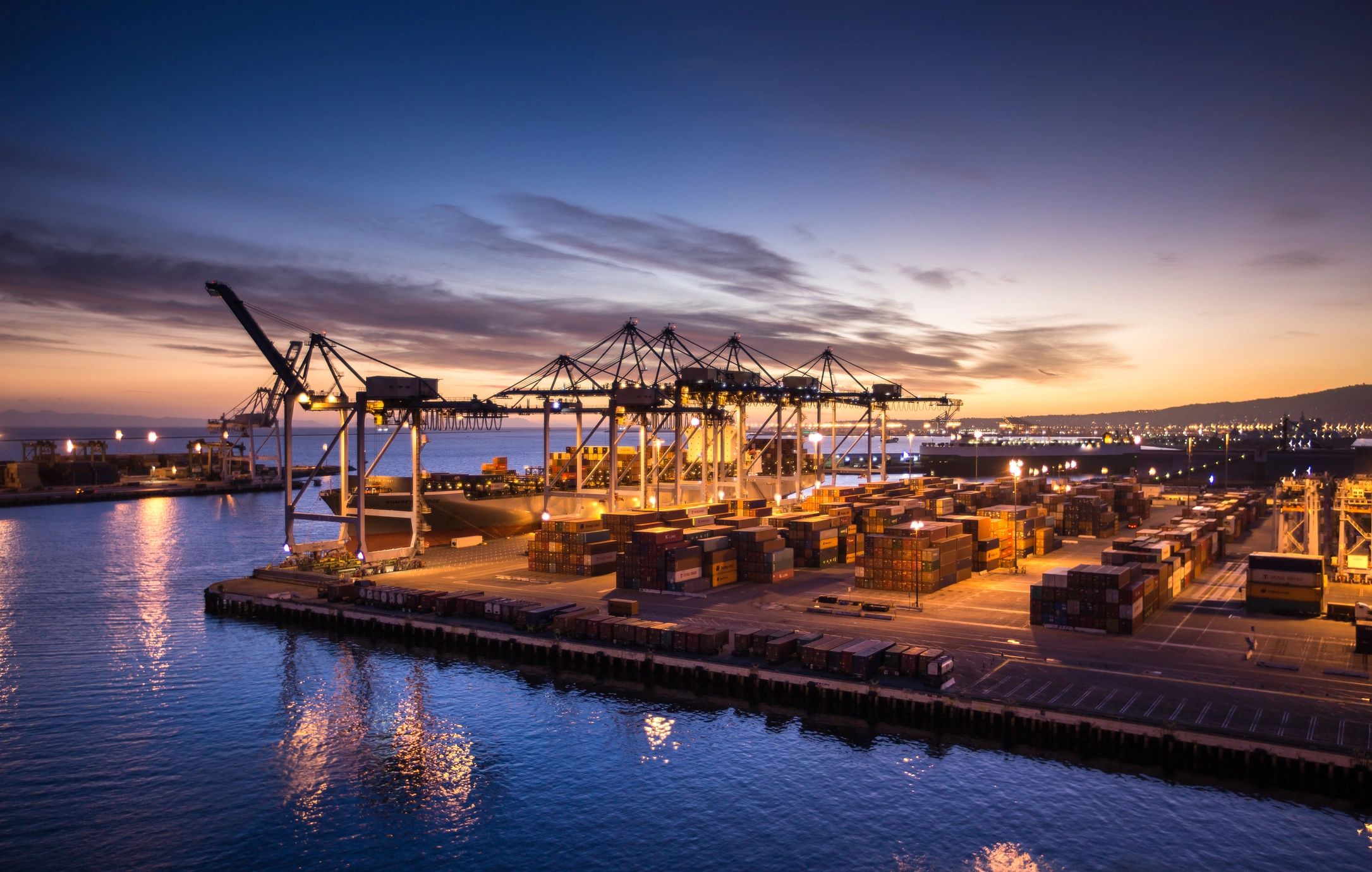 Container port with cargo cranes and shipping containers at twilight
